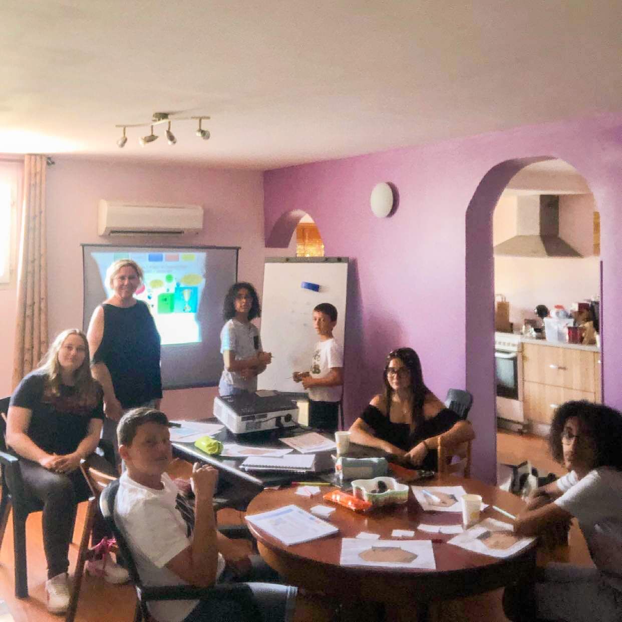 Jeunes stagiaires autour d'une table, l'un d'eux debout devant l'écran