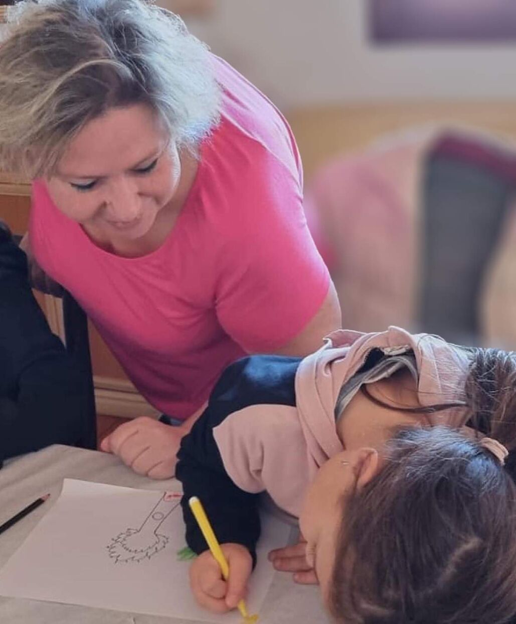 La formatrice penchée auprès d'une jeune stagiaire qui dessine
